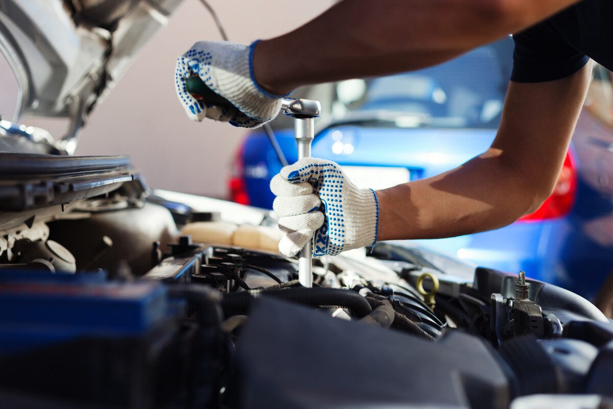 Meccanico al lavoro sul vano motore di un'auto in officina a Como